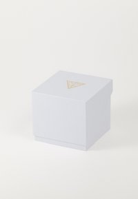 Witte vierkante sieradenbox met een gouden, geperst Guess-logo in de vorm van een driehoek, gecentreerd op het deksel tegen een effen achtergrond.