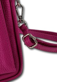 Fuchsia leren handtas met een gestructureerde afwerking, een afneembare band bevestigd met een zilverkleurige metalen clip, en accentsteken.