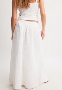 Weißer Maxi-Rock mit Lochstickerei, gerafftem Bund und fließendem Design, der zu einem taillierten weißen Crop-Top passt.