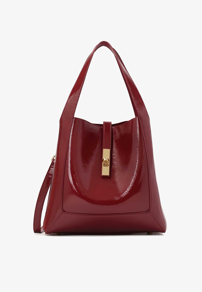 Punainen kiiltävä käsilaukku, jossa on rakenteellinen muotoilu, ja jossa on huomattava kultainen varuste. Silkkinen pinta ja geometrinen muoto.