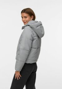 Sivi puffer jakna s kapuljačom, sa qpadded quilted punjenjem, prilagođenim siluetom i elastičnim manžetama. Glatka tekstura, minimalni elementi dizajna.