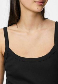 Must mustriba tank top, mille õhukeste rihmadega ja ruudukujulise kaelusega, millel on tekstuuriga kangas ja sile viimistlus.