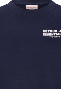 Granatowy sweter z ribbowanym okrągłym dekoltem, z białym nadrukiem tekstu "RETOUR J ESSENTIAL IT STARTS WITH." Miękka tekstura materiału.