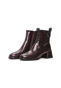 Bottes basses en cuir verni bordeaux avec un talon épais, une fermeture éclair, et un détail de boucle latérale, présentant une surface texturée et une finition lisse.
