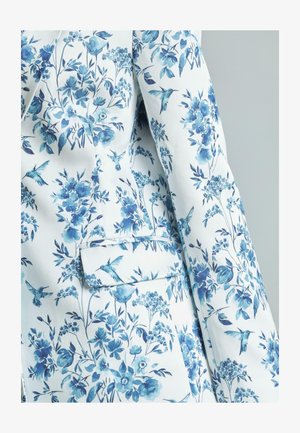 Jas met bloemenpatroon, bestaande uit een witte stofbasis met blauwe bloemen en kolibries, enkele zakdetail, gladde textuur.
