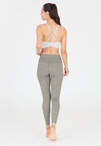 Lichtblauwe sportbeha met gekruiste rugbandjes, gecombineerd met hooggewaisted gestreepte leggings in een grijs en beige motief.