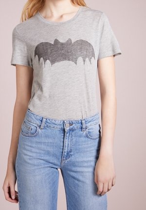 Szara bawełniana koszulka z czarnym nadrukiem sylwetki nietoperza, krótkimi rękawami i okrągłym dekoltem. Połączona z jasnoniebieskimi, wysokim stanem jeansami.