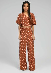 Ensemble deux pièces à pois marron composé d'un haut croisé court à manches bouffantes et de pantalons larges, tous deux ornés de grands pois blancs.