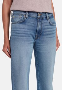 Jeans azzurri chiari realizzati in denim, caratterizzati da una vestibilità aderente, stile a cinque tasche e leggere sfumature sulla parte anteriore per dettagli di trama.