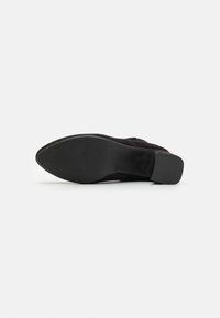 Černé semišové boty na vysokém podpatku s špičatou špičkou, texturovanou stélkou a hladkou gumovou podešví. Výška podpatku je přibližně 7 cm.
