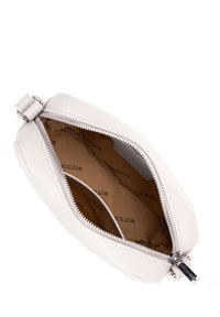 Piccolo sacchetto in pelle beige chiaro con cerniera aperta, che mostra l'imbottitura in tessuto marrone con marchio e una tasca interna.