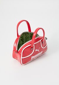 Röd konstläderhandväska med vita detaljer, dragkedjestängning och grön mönstrad interiör med Puma-logotyp. Dubbla korta handtag.