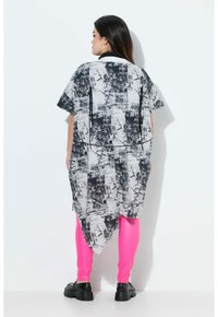 Abito camicia a maniche corte con motivo in bianco e nero, dalla vestibilità ampia, con orlo asimmetrico e cerniere laterali, abbinato a leggings fucsia.