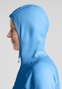 Felpa aderente blu con colletto alto e cappuccio integrato, realizzata in un tessuto liscio. Presenta una cerniera frontale e cuciture minime.