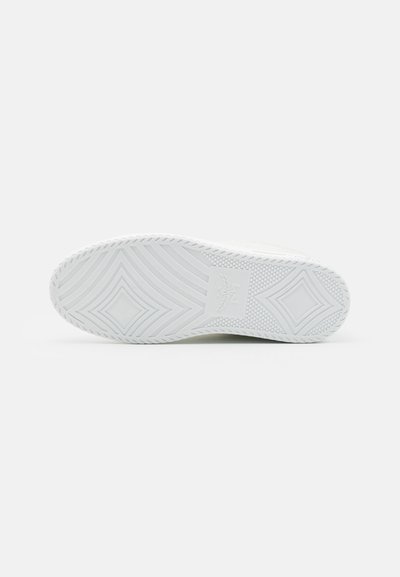 Suela de zapato de goma blanca que presenta un patrón de tracción en zigzag, acentos rectangulares y un logo en el centro, con una superficie texturizada para mayor agarre.