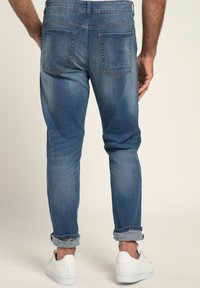 Jeans de mezclilla de color azul claro con corte ajustado, puños enrollados y bolsillos traseros. El material muestra un ligero desgaste y tiene una textura suave.