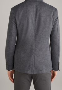 Giacca su misura in tessuto grigio scuro testurizzato, caratterizzata da una vestibilità slim, rever a notch e polsini con bottoni, con dettagli delle cuciture visibili.
