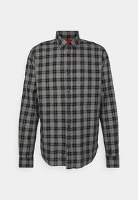 Camisa de cuadros en negro y gris, de botones, con mangas largas, cuello puntiagudo y botones negros. Presenta una textura de tela suave y un dobladillo curvado.