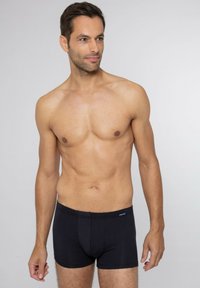 Svarta boxertrosor i mjukt material med en subtil randig mönster och resårmidja som har en blå logotags.