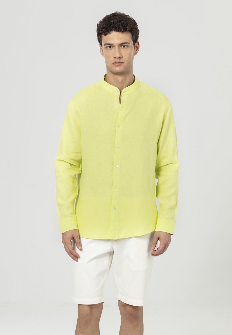 Linnen overhemd in felgeel met een bandkraag, lange mouwen en knoopsluiting. Gepaard met witte shorts, eenvoudig ontwerp, lichtgewicht textuur.