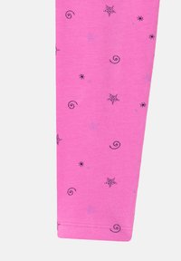Leggings in cotone rosa con motivi di stelle e spirali neri e viola su tutta la superficie. Tessuto morbido con orlo cucito nella parte inferiore.