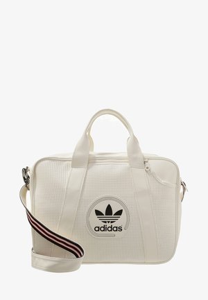 Sac de sport Adidas blanc avec texture perforée, double anses, fermeture éclair sur le dessus et bandoulière rayée amovible.