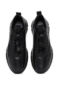 Sneakers neri con una tomaia in pelle liscia, punta rotonda, design con lacci, dettagli testurizzati e suole in gomma. Linguetta sul tallone.