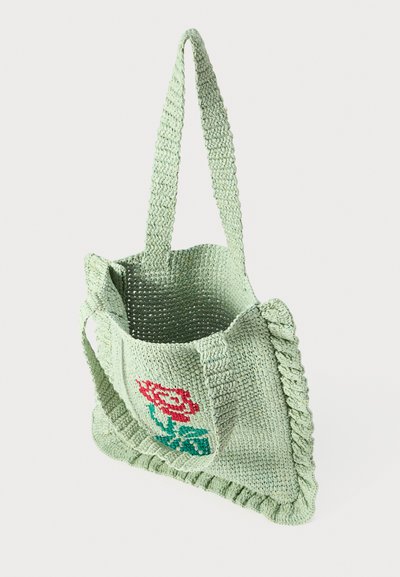 Geantă de tote tricotată, verde, cu un design floral în roșu și albastru. Are o suprafață texturată și margini franjurate, cu două mânere subțiri.