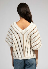 Pull en maille blanche avec col en V, manches courtes et rayures horizontales. Comprend des détails en dentelle et une coupe décontractée.