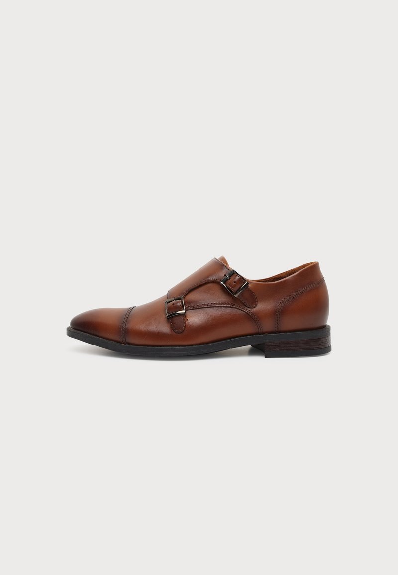 Chaussure habillée pour homme en cuir marron avec boucles double bride de moine et semelle noire, présentée en profil latéral sur fond blanc.