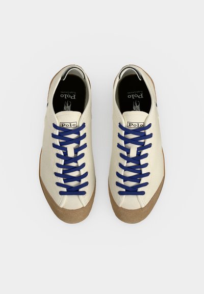 Ζευγάρι λευκά αθλητικά παπούτσια Polo Ralph Lauren με μπλε κορδόνια και καφέ λαστιχένιες σόλες, από πάνω σε λευκό φόντο.