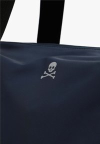 Bolso tote azul marino hecho de tela duradera con un gráfico en gris de calavera y tibias cruzadas. Incluye asas negras para llevar.