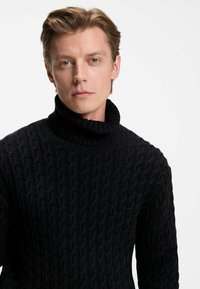 Marineblaue Rollkragenpullover aus strukturiertem Strickstoff mit hohem Kragen und taillierter Silhouette.