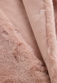 Weicher rosa Kunstpelzmantel mit passendem gestricktem Innenfutter und kleinen runden klaren Knöpfen entlang des Randes.