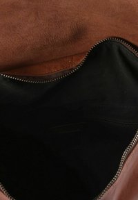 Bolso de ante marrón y cuero con cierre de cremallera. El interior cuenta con un forro de tela negra y un bolsillo con cremallera. Textura suave y diseño sencillo.