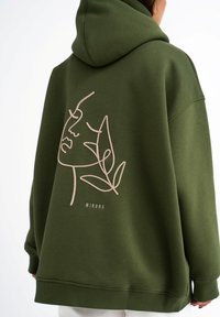 Olijfgroene hoodie van zachte stof met een minimalistisch geborduurd gezicht en bladdesign in lichtbeige op de rug.