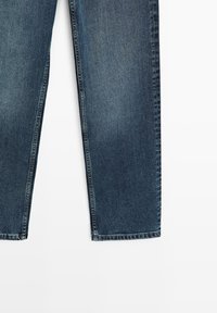 Jeans in denim blu scuro a taglio dritto con sfumature leggere e orli doppiamente cuciti su sfondo bianco.