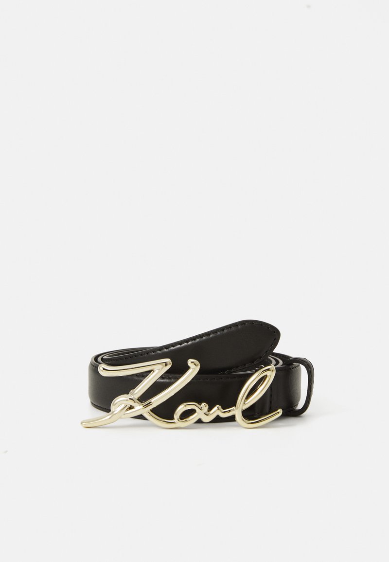 Ceinture en cuir noir enroulée avec une boucle en or en forme de texte en cursive "Karl" sur fond blanc.