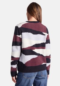 Multicolored sweater featuring a pattern of jagged stripes in burgundy, black, grey, and white, with a ribbed hem and soft texture.
