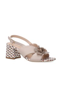 Beige leren slingback schoen met een bloemenaccent en een blokhak met geometrisch patroon in rood, wit en zwart. Open teen ontwerp.