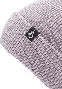 Purple knit beanie with a textured pattern. Features a black label with a logo on the side. Soft, flexible fabric allows for a snug fit.