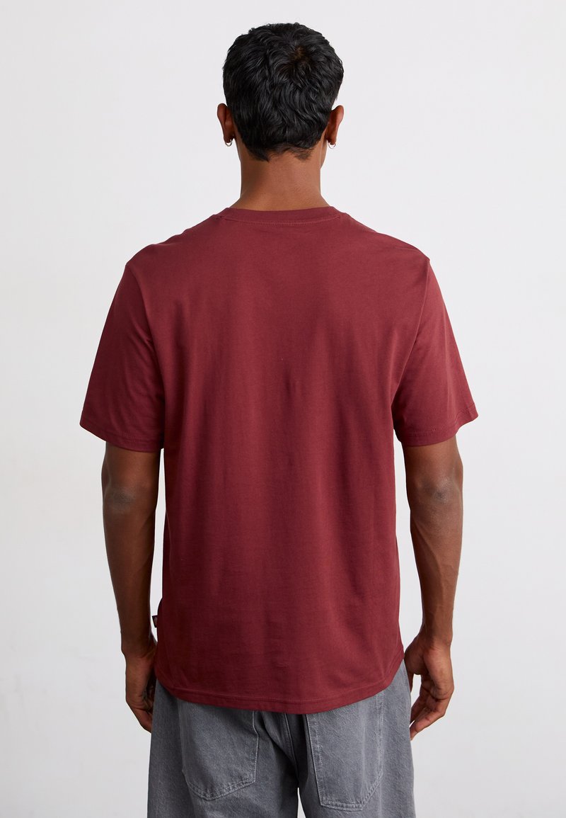 Bordeaux katoenen t-shirt met korte mouwen, ronde hals en een relaxed fit. Gladde textuur en een effen achterkant zonder logo's of patroon.