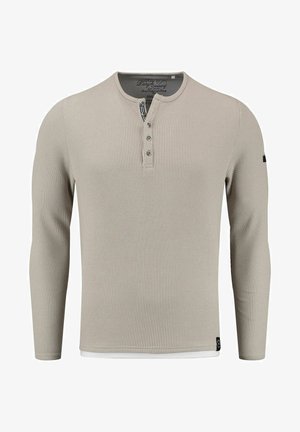 Camisa de manga larga beige de canalé con cuello tipo henley, tapeta de tres botones y bajo interior en blanco; hecha de una tela texturizada.