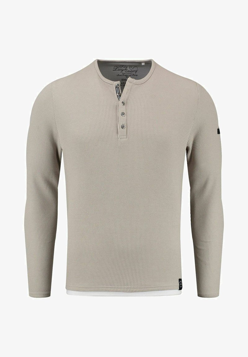 Camisa de manga larga beige de canalé con cuello tipo henley, tapeta de tres botones y bajo interior en blanco; hecha de una tela texturizada.