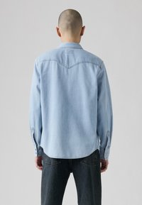 Lichtblauw denim shirt met een schouderpas ontwerp, lange mouwen, knoopmanchetten en een afgeronde zoom. Soepele textuur, casual pasvorm en minimale detailing.