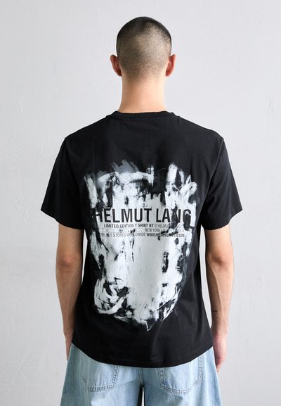 Fekete pamut póló, a hátán egy nagy absztrakt fehér és szürke grafikával, amelyen a márkát és a kiadást részletező szöveg található.