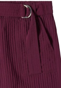 Jupe prune taille haute avec plis verticaux texturés, munie d'une large ceinture en tissu avec boucle double anneau argentée et poche plaquée latérale.