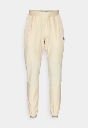 Light beige track pants with a smooth texture, featuring contrasting panels, elastic waistband, and elastic cuffs at the ankles.