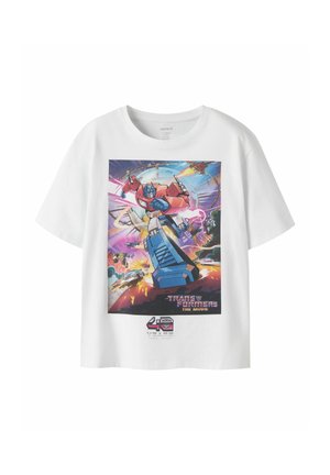 T-shirt blanc avec un graphisme coloré d'Optimus Prime de Transformers avec des explosions et des vaisseaux spatiaux, célébrant 40 ans.