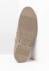 Chaussure en suède beige avec une semelle en caoutchouc texturé, présentant un logo en relief, un dessus lisse et un design à bout rond. Taille marquée comme 42.